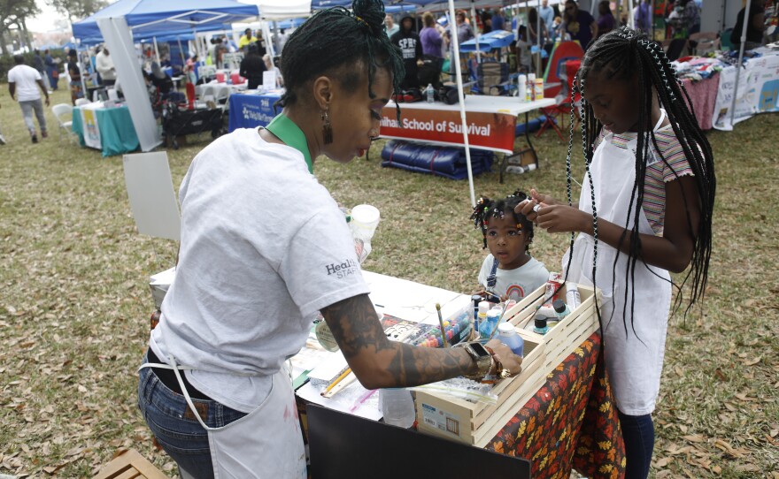 Miesha Brundridge helps Ava Hardy and her sister Joyce at her art booth during the 2022 Publix Tampa Bay Collard Festival in St. Petersburg, Florida, on Saturday, February 19, 2022. Photo by Octavio Jones for WUSF