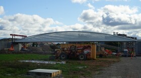A grey pedestrian bridge installed on a construction site with a blue sky and white clouds. 