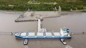 A pair of tugboats push a tanker against a dock