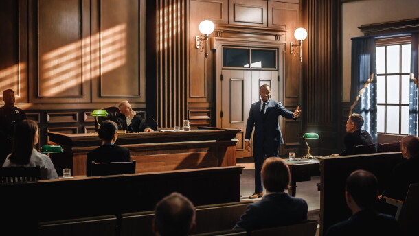 Stock image of a male public defender making a passionate speech to a judge and jury.