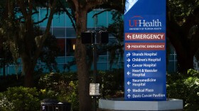 UF Health Hospital in Gainesville, Fla. Blue sign outside with trees in background. 