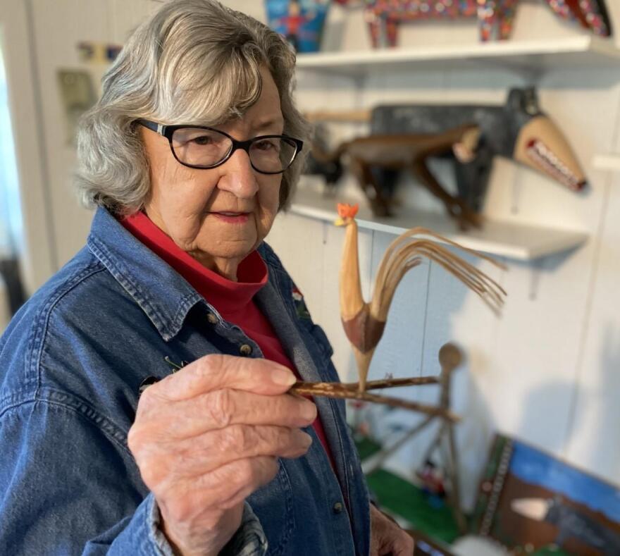 Minnie Adkins holds up the first rooster she ever carved.