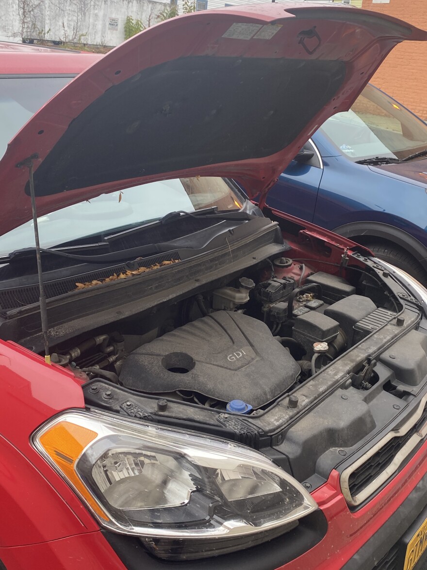 Red kia soul with hood popped. 