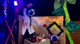 A figure of an eyeball with a lab coat and a lobster claw at a desk.