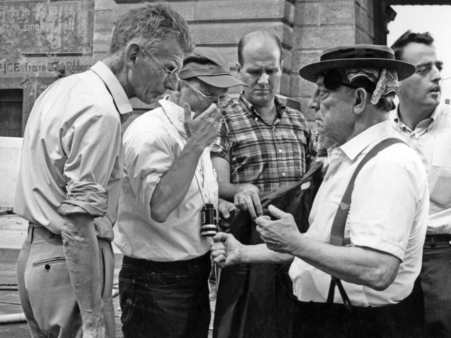 Samuel Beckett (left), Alan Schneider (in baseball cap) and Buster Keaton (right) on the set of <em>Film</em>. Presumably, they're discussing a scene, not staring each other down.