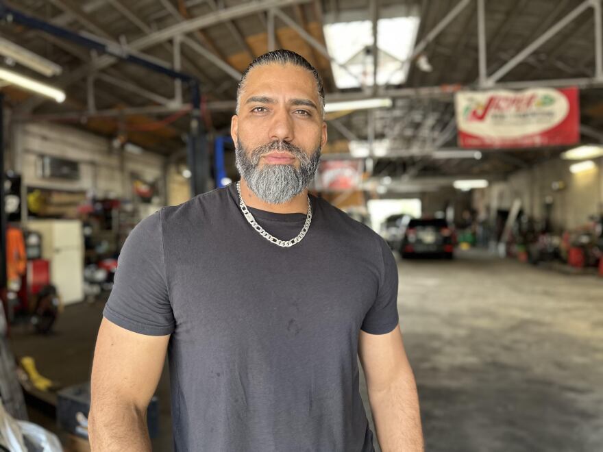 Auto repair shop owner Danery Berrios stands in his shop