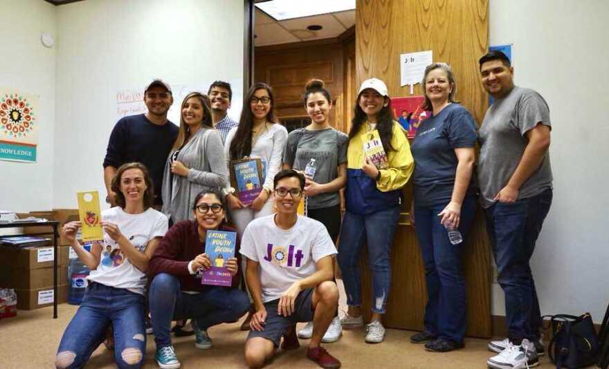 Young political organizers pose with their "Latinx Voters Decide" flyers before a voter registration event hosted by the political collective Jolt. David Sanchez (far right), a Latino political organizer is leading the group.