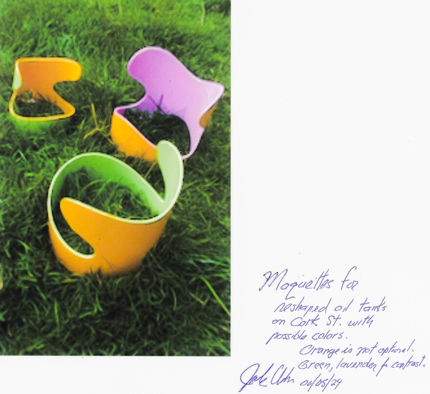 A photocopy of a photo of a proposed art project to repurpose the tanks. The model for a larger structure sits in the grass and is a little out of focus. To the right of the photo is a note signed by Jack Urban. The note reads, "Maquettes for reshaped oil tanks on Cork St. with possible colors. Orange is not optional. Green, lavender for contrast." The note is dated June 5, 2024.
