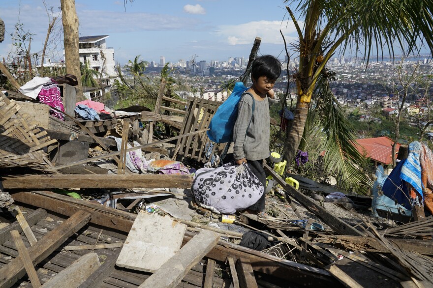 Romel Lo-ang recovers personal belongings on Sunday from what's left of his family's home damaged by Typhoon Rai in Cebu province, central Philippines.