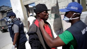 A worker with Haiti's Ministry of Public Health and Population checks the temperature of a Haitian man coming from the Dominican Republic on March 5.