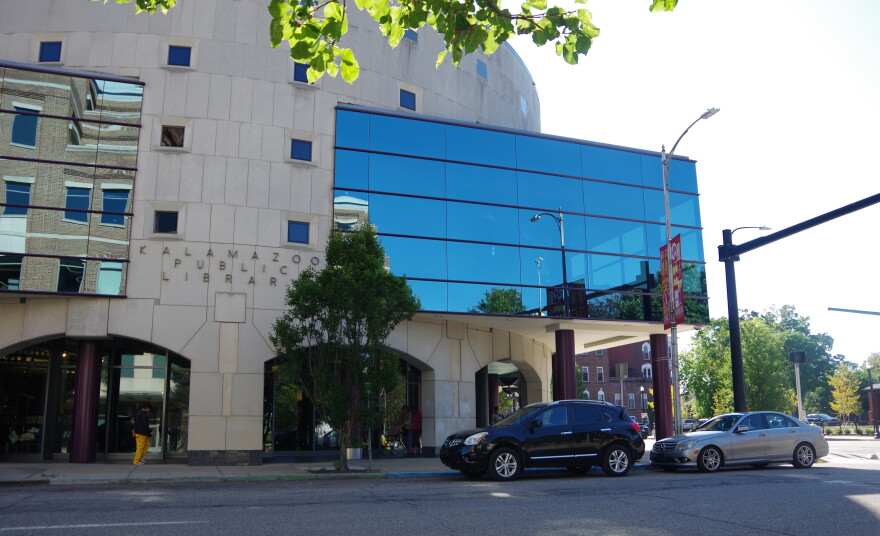 Exterior photo of modern building with concrete curving wall and glass window box with reflective surface