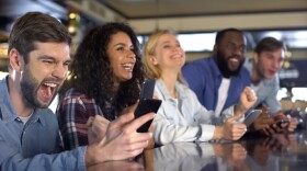 Sport fans betting online using their cell phones at a bar. 