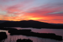 The run rising over Squam Lake with yellow, orange, pink and purple hues.