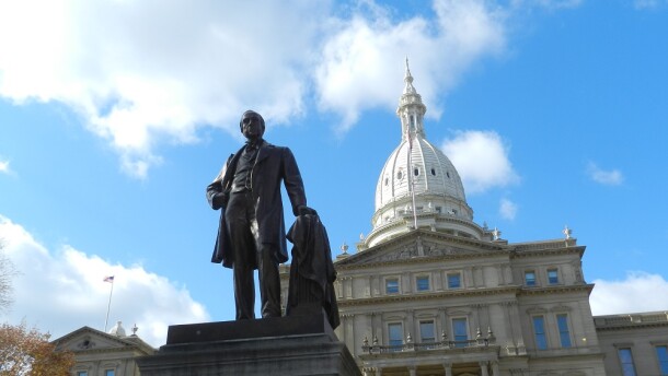 Michigan Capitol Building and Gov. Austin Blair statue against a blue sky.