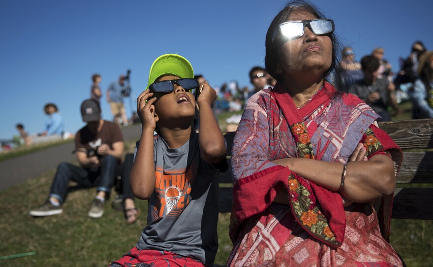 Ayush Jakhotia, 7, left, watches the solar eclipse with his grandmother, Radha Jakhotia, right, on Monday, August 21, 2017, from Gas Works Park, in Seattle. KUOW Photo/Megan Farmer