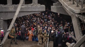 Ukrainians crowd under a destroyed bridge as they try to flee crossing the Irpin river in the outskirts of Kyiv, Ukraine, Saturday, March 5, 2022. (AP Photo/Emilio Morenatti)