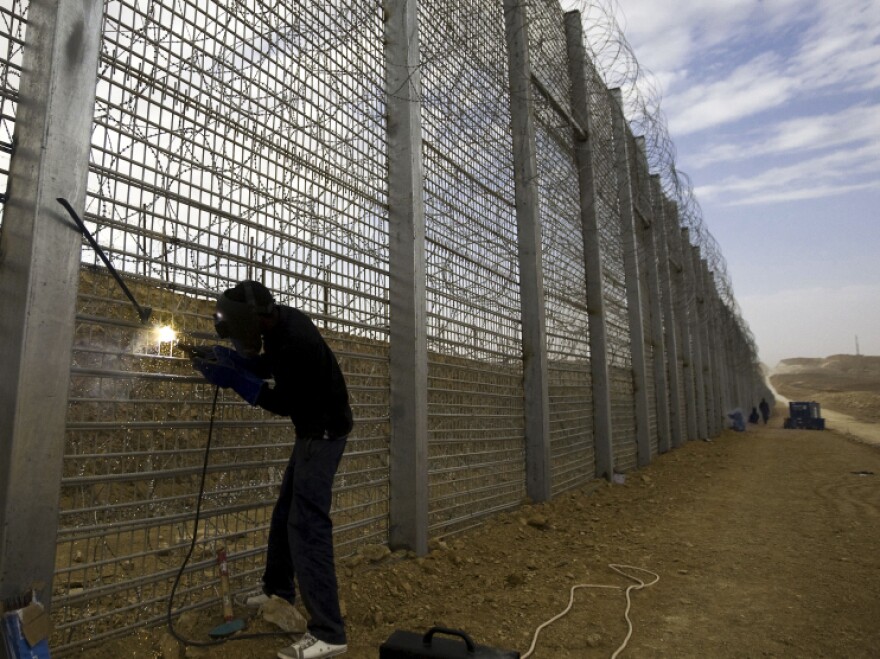 A worker builds part of Israel's border fence near the Red Sea resort town of Eilat in February. Many illegal immigrants to Israel slip across the country's border with Egypt.  