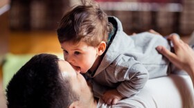 This stock image shows a baby and father playing at home. New research finds that babies judge the relationship between two people by whether or not they willingly share saliva.