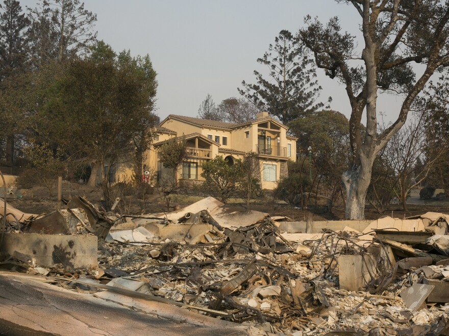 A large home that survived last week's wildfire sits by the burned ruins of another nearby home, on Monday in Santa Rosa, Calif.