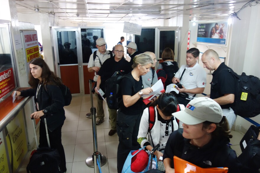 Our blogger Michaeleen Doucleff (in NPR cap) waits in line at Liberia's Roberts International Airport.