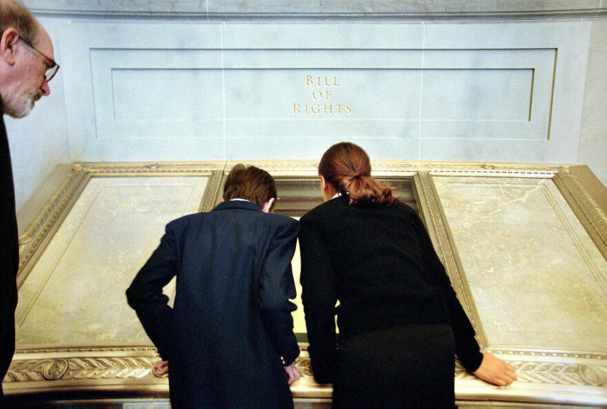 Dennis A. Daellenbach, the Director of the Gerald R. Ford Presidential Library And Museum, left, looking over their shoulders, Adam Jennison, 13, of NW DC, middle, and Madeleine Joseph, 13, of Northwest Washington, take their first peek at the actual Bill of Rights document, Wednesday, September 17, 2003. President George W. Bush joined others to celebrate the re-opening of the National Archives Rotunda after a two-year renovation, in Washington, DC.