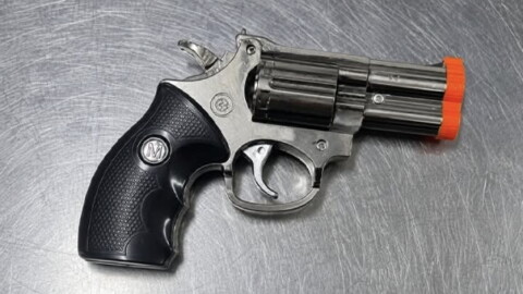 A cigarette lighter that look like a handgun with a black handle and silver barrel.