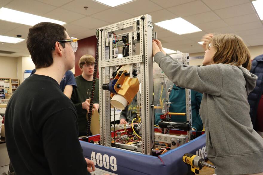 A half dozen people gathered around a robotic structure