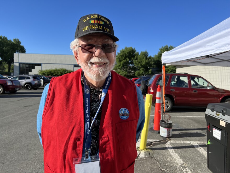 John Vettel stands in a greeting area outside of a polling location. His hat identifies him as a United States Air Force veteran of the Vietnam War. 