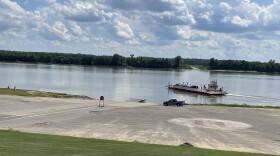 A red and white ferryboat makes its way in the middle of the Ohio River.