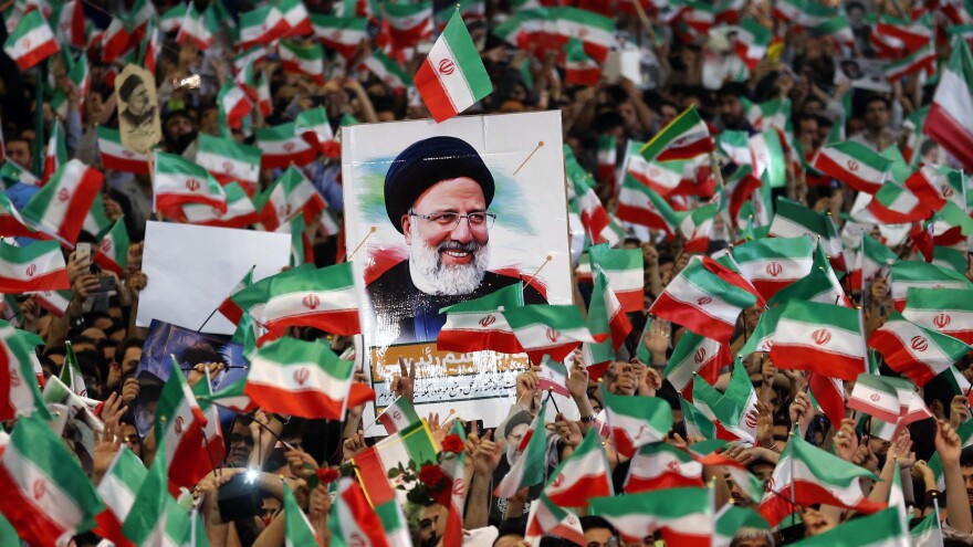 Ebrahim Raisi's supporters loft national flags and his portrait during a campaign rally at Imam Khomeini Mosque in Tehran on Tuesday.