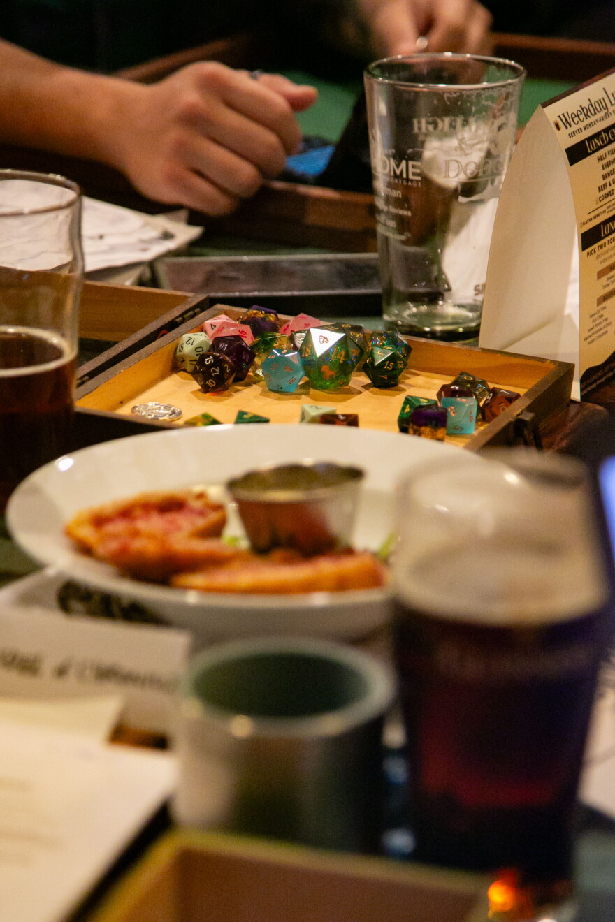 Dice in a box on a table with appetizers and drinks.