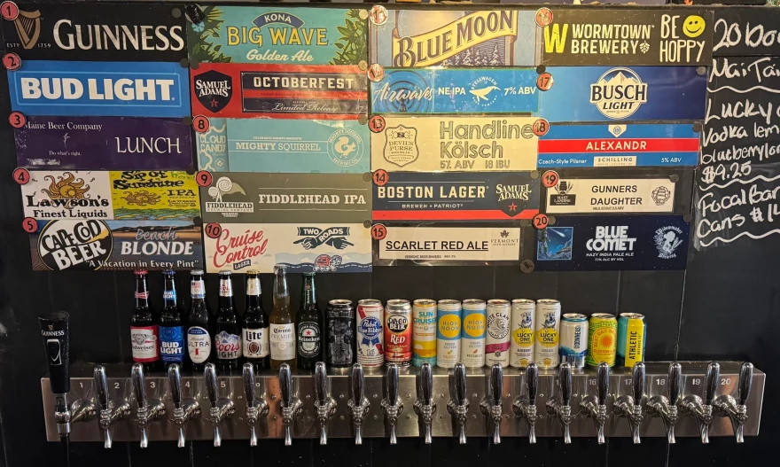 A display of beer taps, bottles and cans with colorful beer brand advertising.