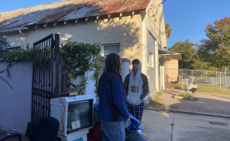 Volunteer Sandor Seely, 16, right, speaks with Jess Larsen as the food pantry winds down. (Nicolette De Value/WUFT News)