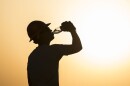 An airman assigned to the 557th Expeditionary RED HORSE drinks water while working on a construction site.