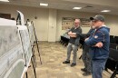 Three West Dayton community members gather around mock-ups of plans for reconstruction on W Third Street in Dayton's City Hall