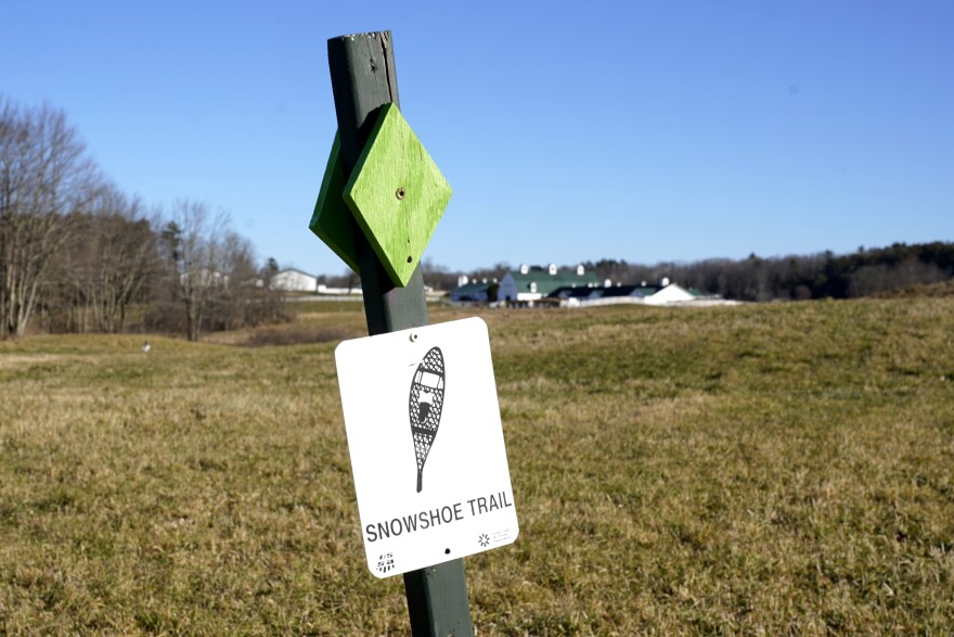 A trail sign for a snowshoeing route is seen on a snowless field at Pineland Farms, Thursday, Dec. 21, 2023, in New Gloucester, Maine.