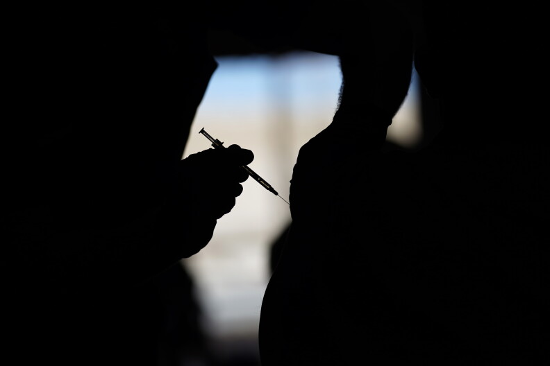 A silhouette of someone receiving a vaccine. 