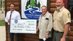 Board Member Derek Jensen accepting a grant from Muskies, Inc in front of the offices of Northern Waters Land Trust in Walker.