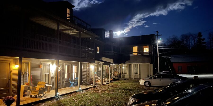 Apartment building with cars parked out front, moonlight in distance