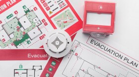 Evacuation plans, smoke detector and manual call point on white background