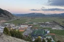 A photo taken from a hillside overlooking the town of Jackson. A track and football field are in the foreground, with mountains behind.
