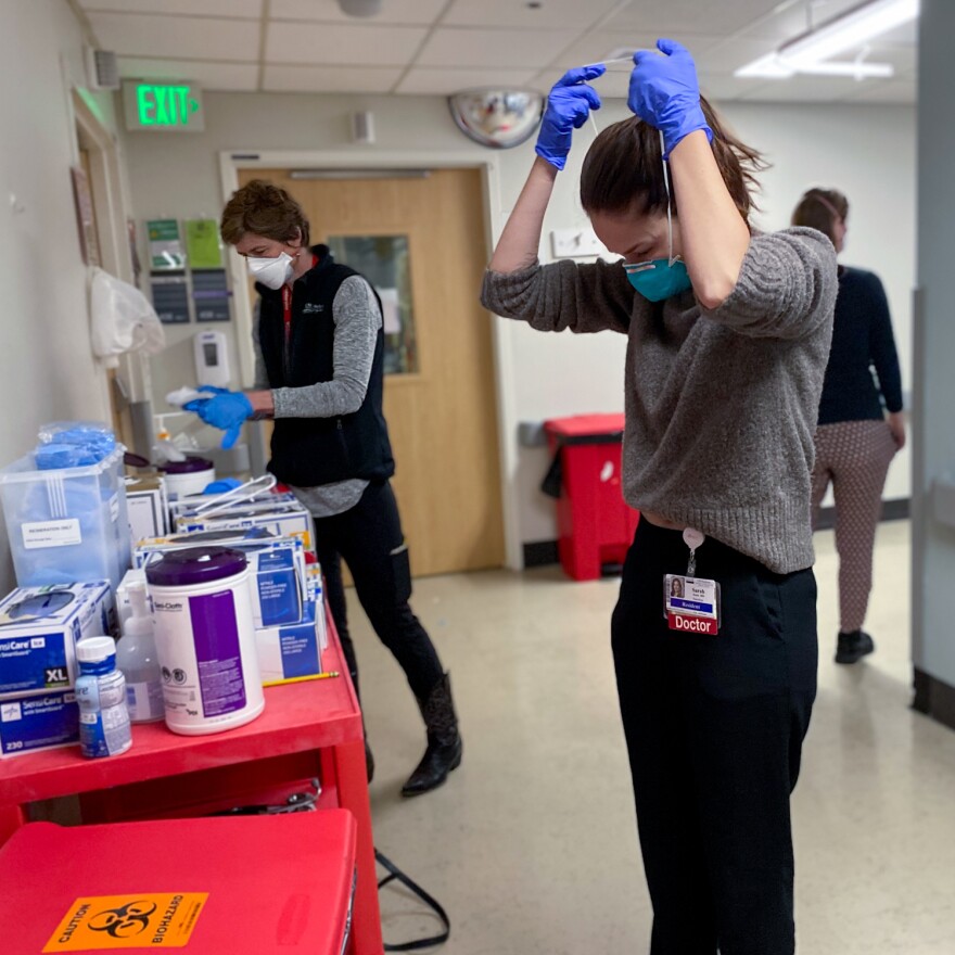 A resident at Harborview Medical Center in Seattle puts on a mask before entering a patient's room in January. During the omicron surge, the rate of hospitalizations fell compared with during the delta surge but the number of omicron cases is significantly higher.