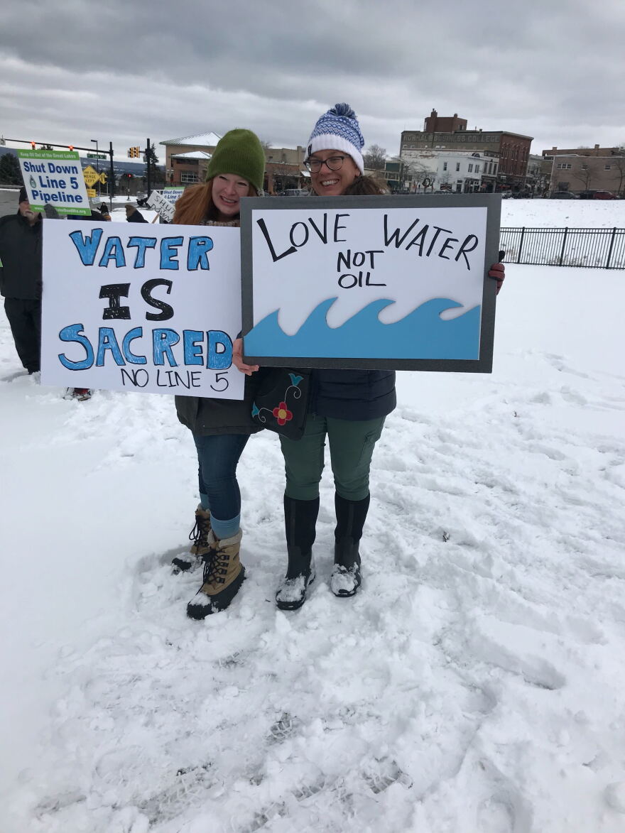 Kristina Persenaire (L) and Denise Petoskey (R) hold water-themed signs. 