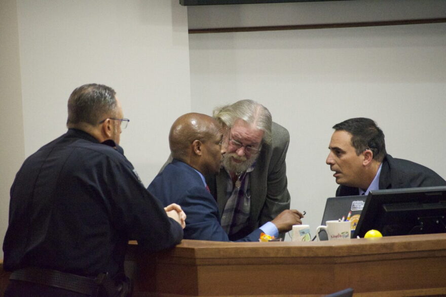 A huddle between North Port Police Department Chef Todd Garrison, City Manager Jerome Fletcher, Mayor Pete Emrich, and City Attorney Michael Fuino during a raucous meeting on data centers.