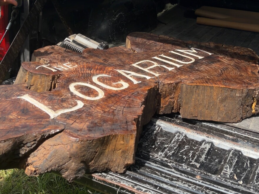A slice of a tree trunk with the words "The Logarium" carved into it