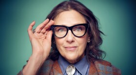 Rebecca Miller pushes her glasses up while smiling at the camera