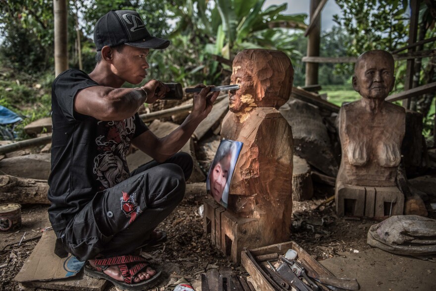 Jeffrey Maguling carves a <em>tau-tau</em> statue for the family of a recently deceased woman. The <em>tau-tau</em> will stand by her grave.