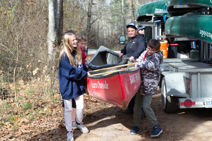 Brielle Ruckman, Kaleb Moyers, Felicity Zimmerman, and Ben Higley carry a canoe to the lake.