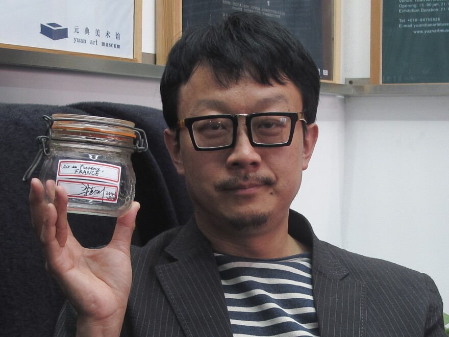 Beijing artist Liang Kegang poses in a Beijing art gallery earlier this week with the jar of fresh air he collected in Provence, France.