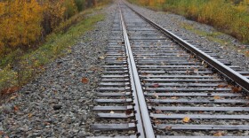 A railroad track leading into yellow leaves